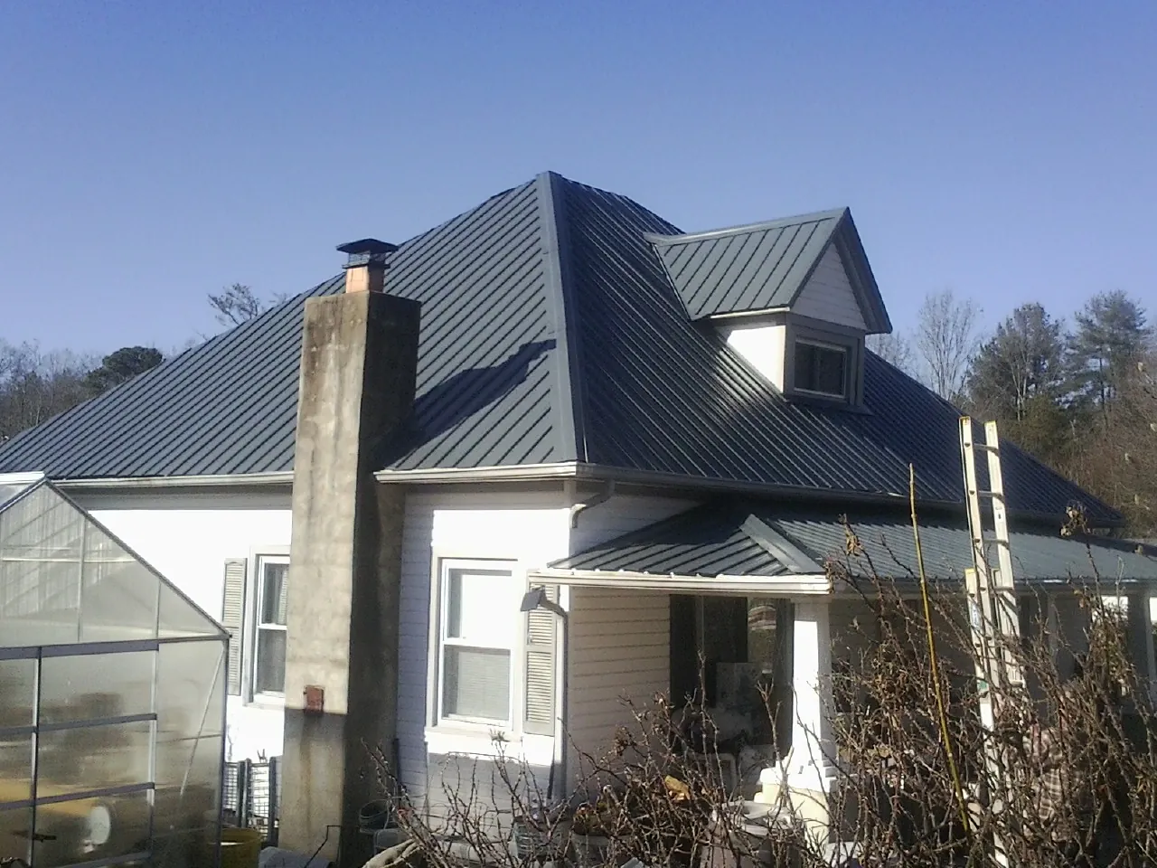 Dark blue standing seam metal roof on a white farmhouse with dormer — Slate & Tile Roof Repair by Roofing Brothers in Idabel