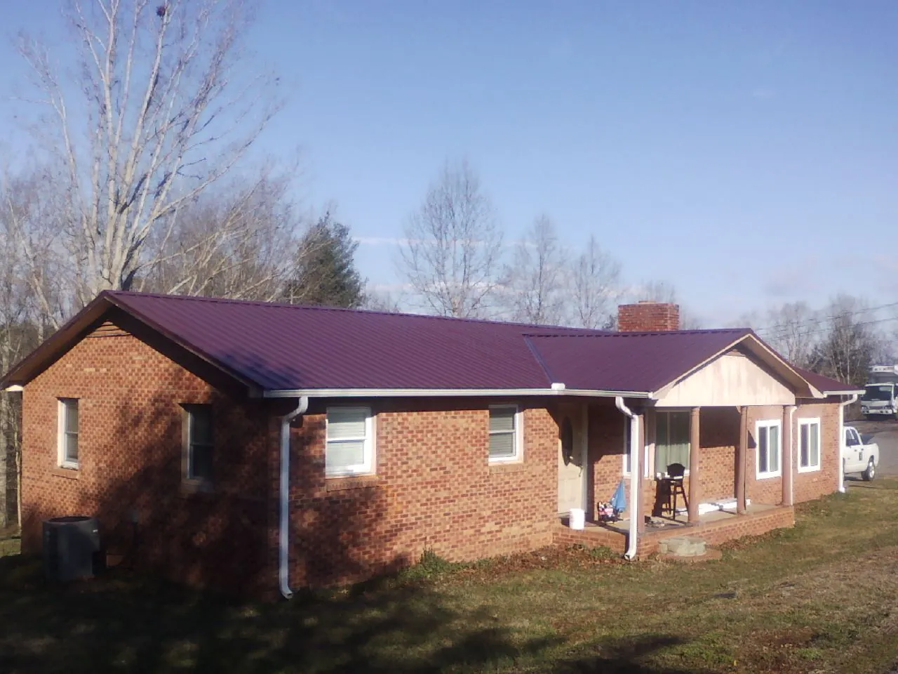 Burgundy metal roof on a brick ranch home with a new addition in Idabel
