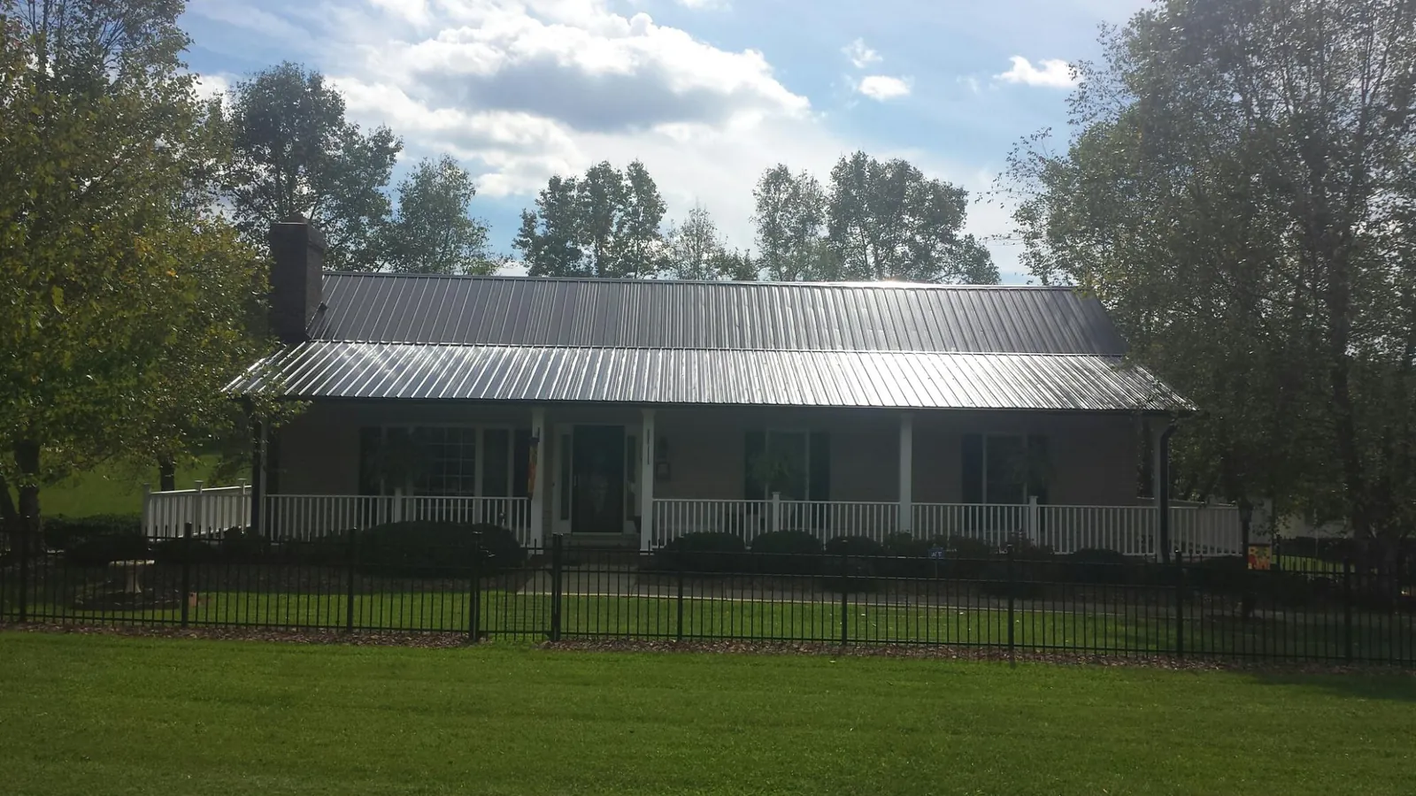 Gray metal roof on a brick ranch with a full width front porch — Gutter Guard Installation work by our crew in Idabel