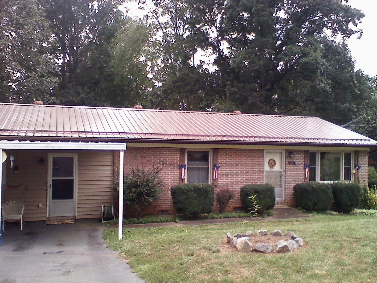 Bronze metal roof and carport on a brick ranch home — Roof Repair work by our crew in Idabel