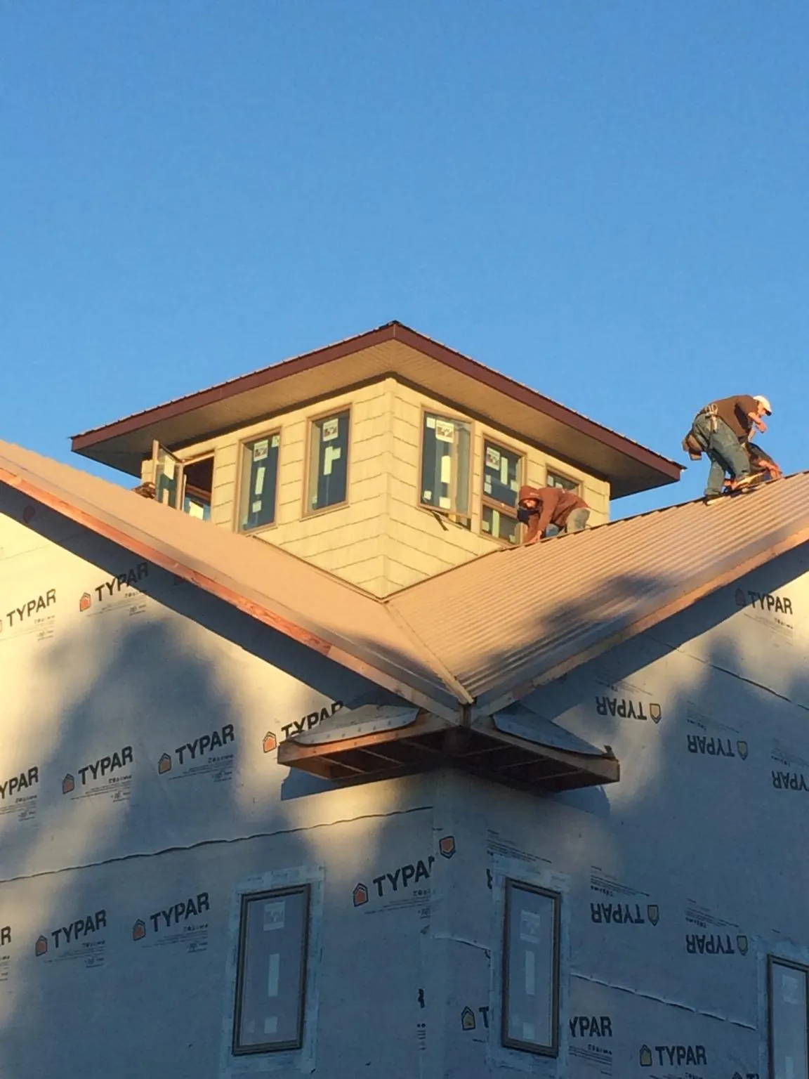 Roofers working around a rooftop cupola on a new metal roof at sunset — Roof Waterproofing in Idabel by Roofing Brothers